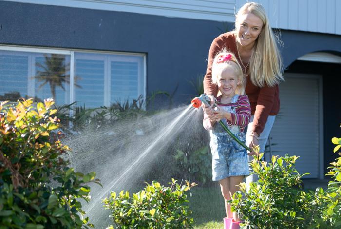 Woman and girl watering a garden with a hose